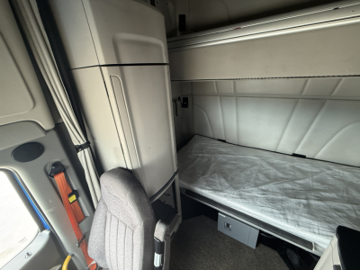 Peterbilt truck sleeper cab interior showing bunk bed with mattress and storage cabinet.