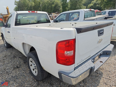 2009 Chevrolet Silverado 1500 pickup truck in a gravel lot, white extended cab with a bed cover, visible rear and left side, Chevrolets emblem on tailgate.