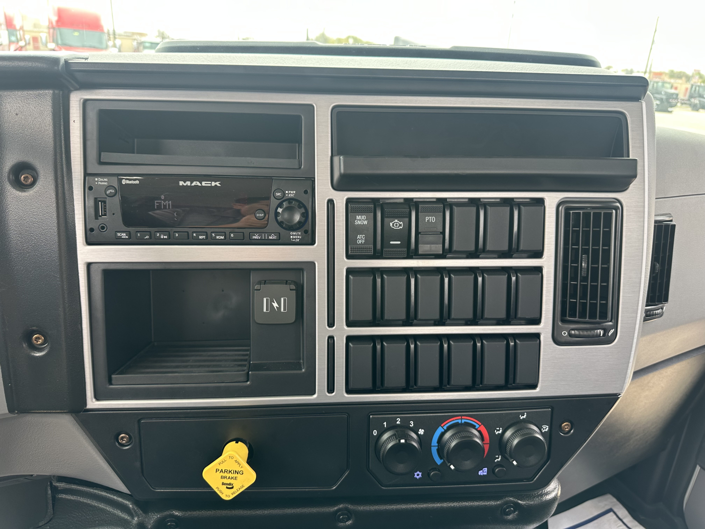 Mack MD6 dash cluster showing radio, climate controls, and switch panel in the center console; various labeled switches and vents visible.