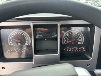 Dashboard of a Mack MD6 truck showing instrument cluster with speedometer 0-120 mph, tachometer, and central display screen. Various indicators and gauges are visible.