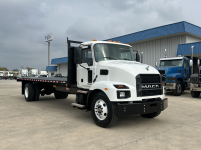 Mack MD6 flatbed truck in white cab with black front grille, showing long flatbed and side steps, daytime outdoor dealership lot.
