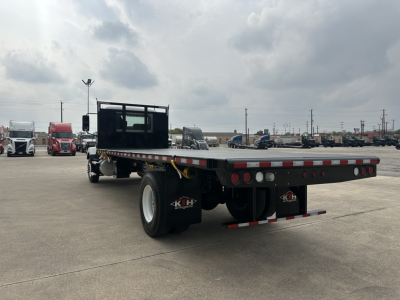 Flatbed truck rear view showing flatbed with black cab, rear dual wheels, and tail lights.