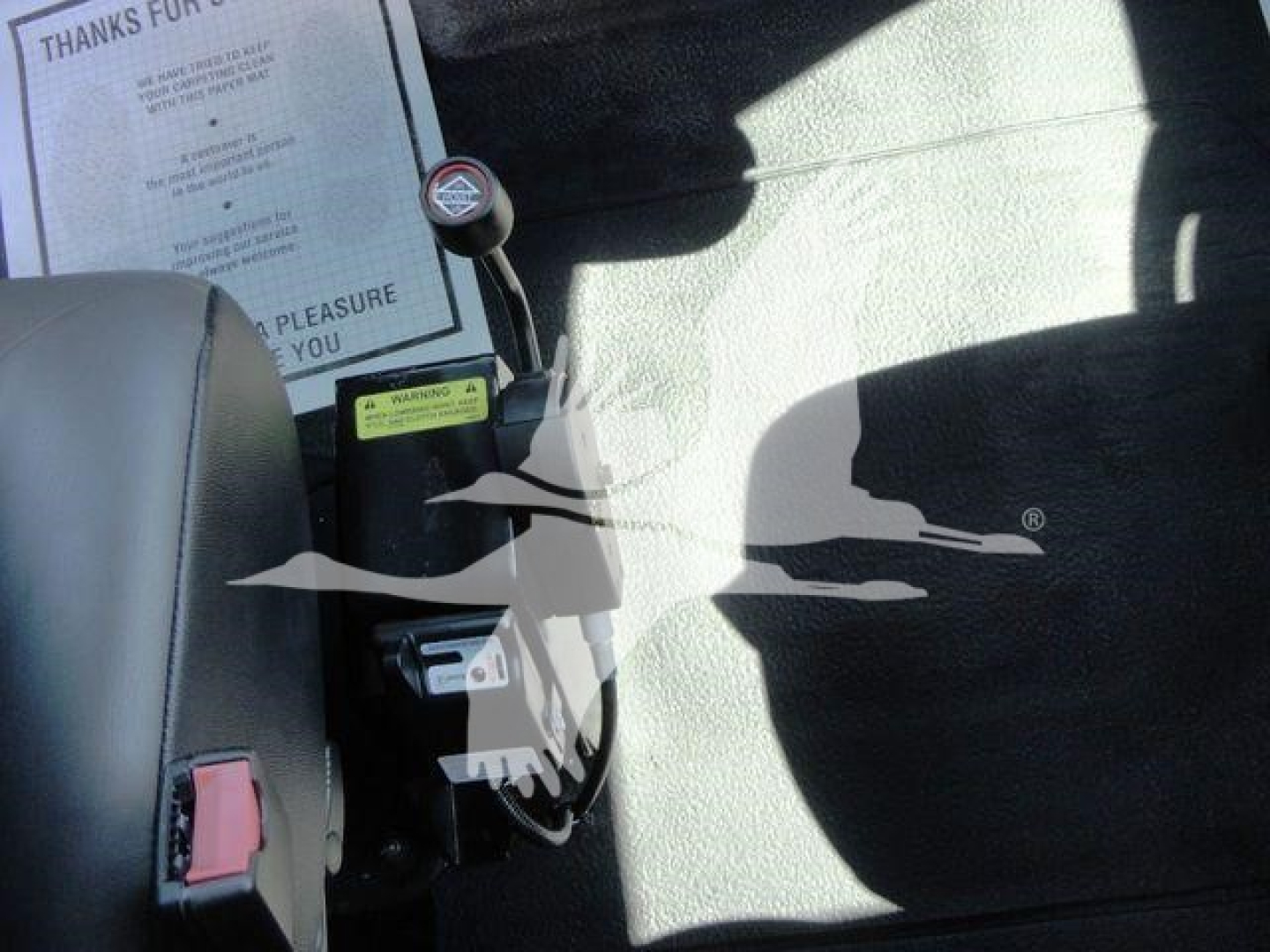 Interior of a 2023 International MV chipper cab showing gear shift lever, control panels, and a document on the seat back with text.