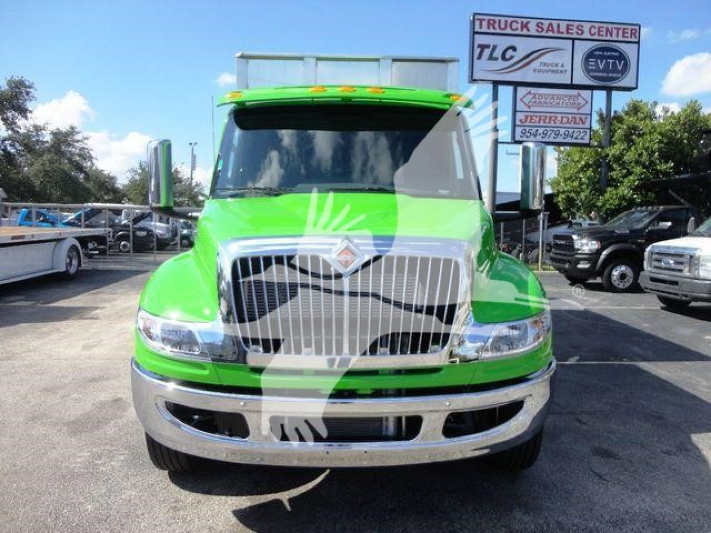 Front view of a bright green 2023 International MV truck in a dealership lot showing chrome grille and bumper.