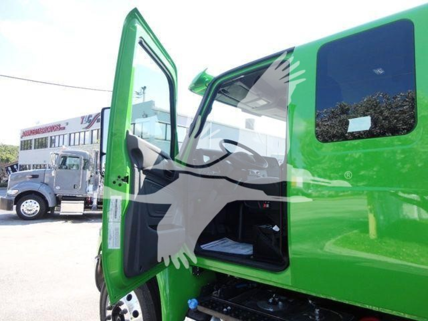 Green International MV cab door open showing interior and steps, exterior window, part of front wheel area.