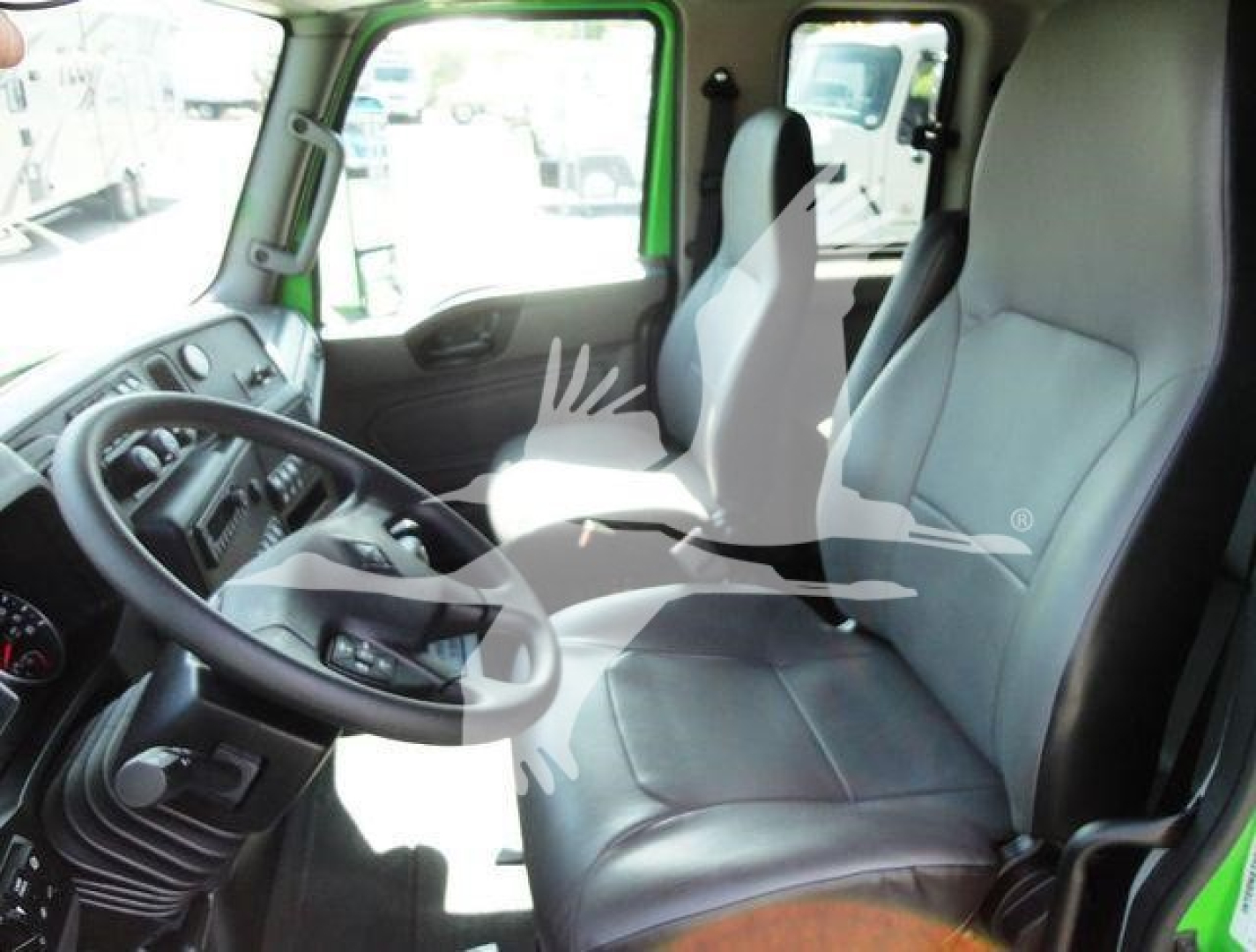 Interior of a 2023 International MV truck cab showing steering wheel, driver seat, and passenger seat in view.