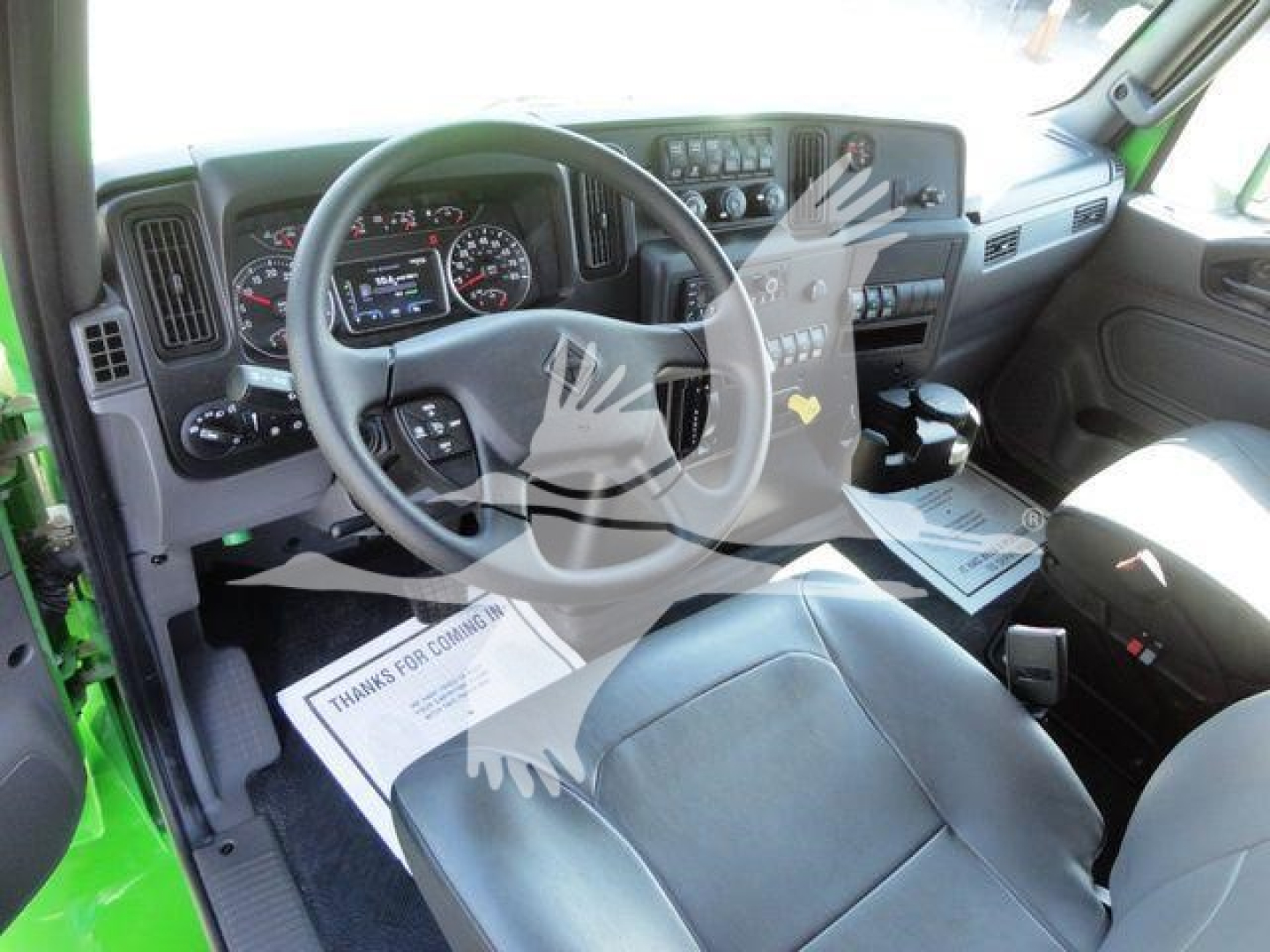 Truck cab interior showing steering wheel dashboard and driver seat in a new International MV chipper truck.