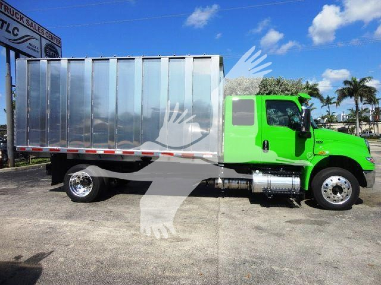 International MV chipper truck side view showing bright green cab and large silver dump body.