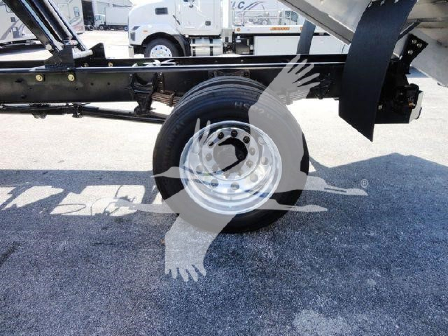 Truck chassis side view showing a wheel and part of the frame under carriage with hydraulic components and a trailer connection.
