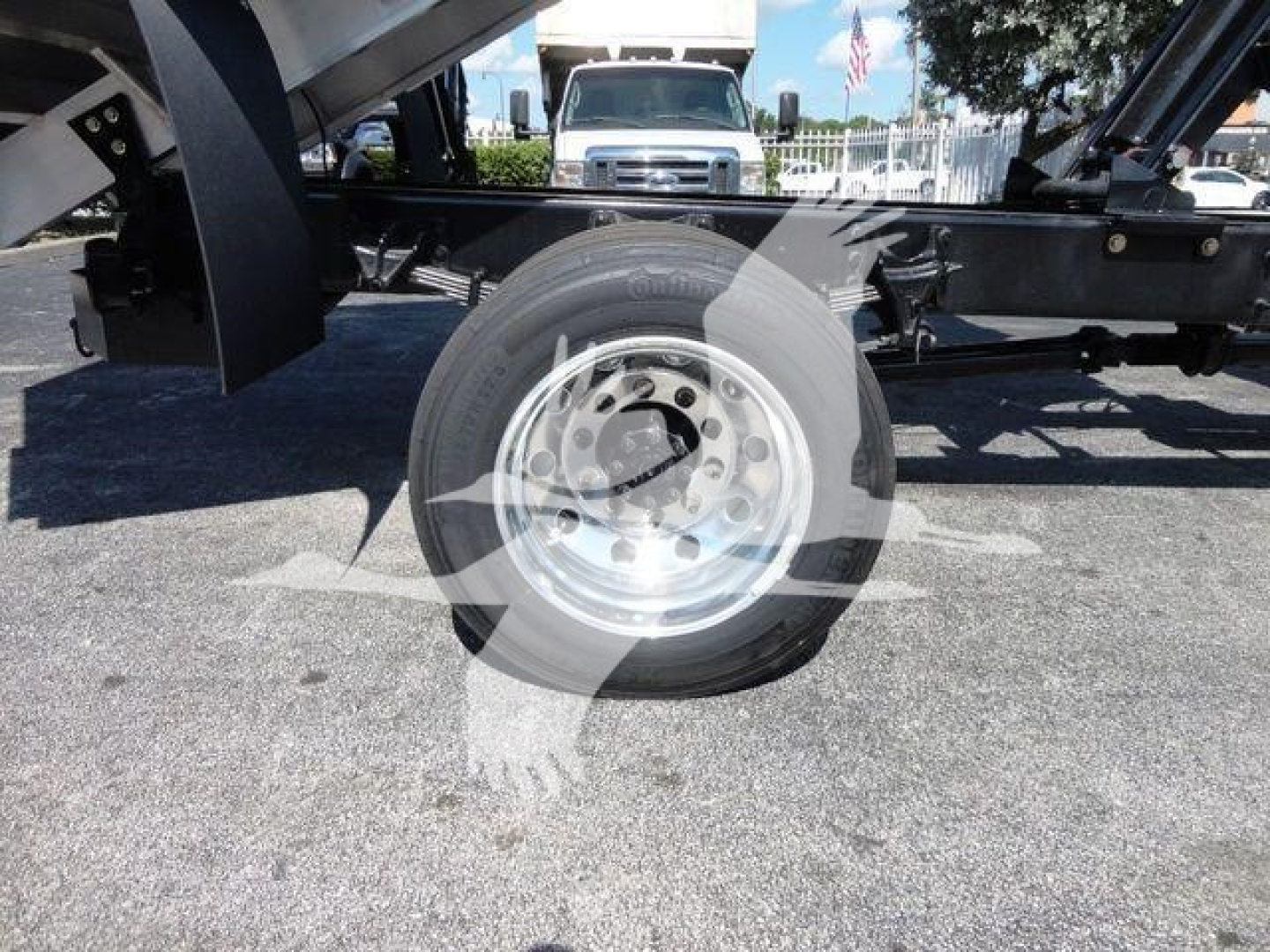 Wheel and undercarriage of a 2023 International MV chipper truck; steel wheel with hub, black chassis, and hydraulic components visible.