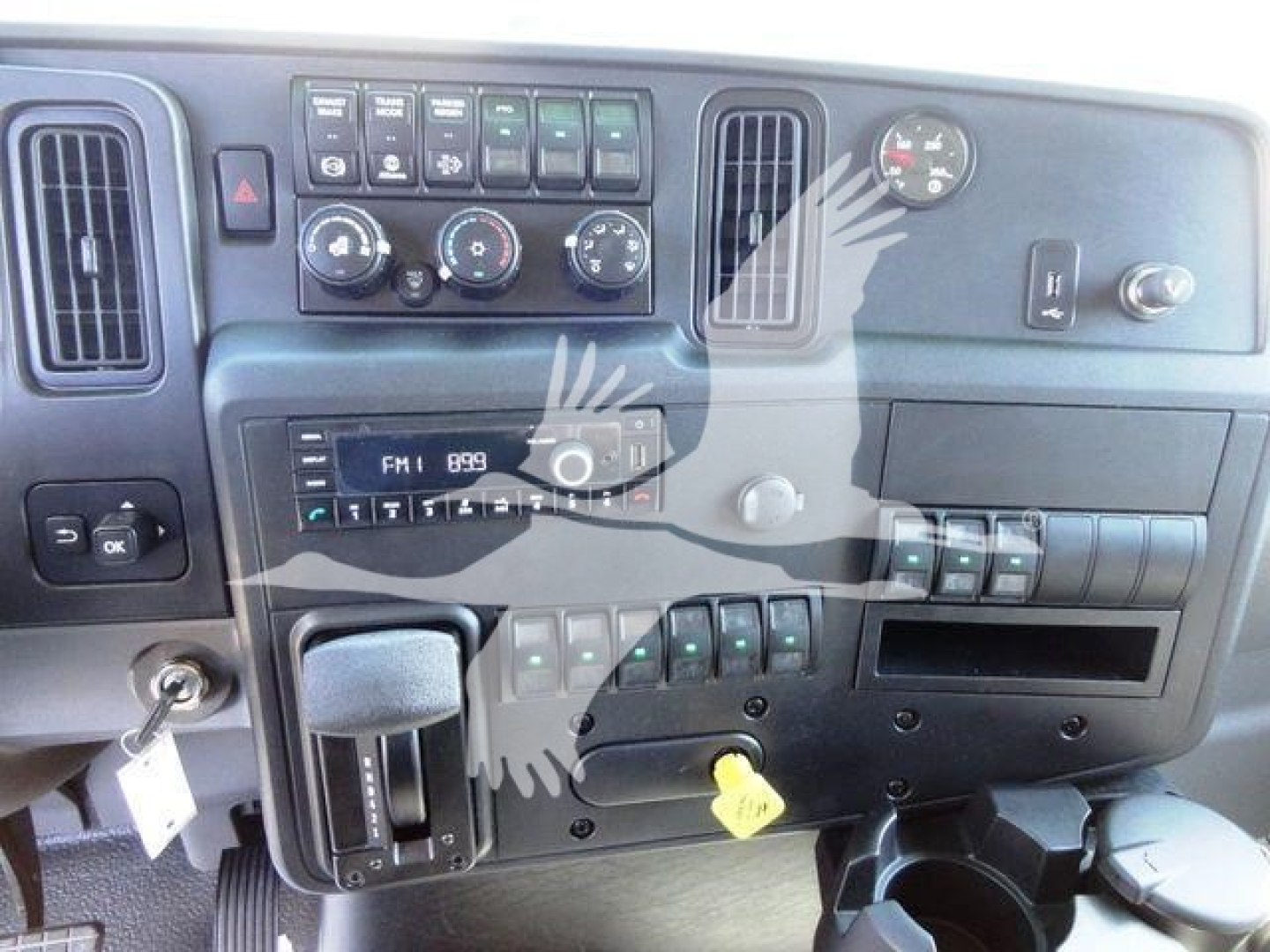 Dashboard of a 2023 International MV chipper truck showing climate controls, radio, switches, and gear selector.
