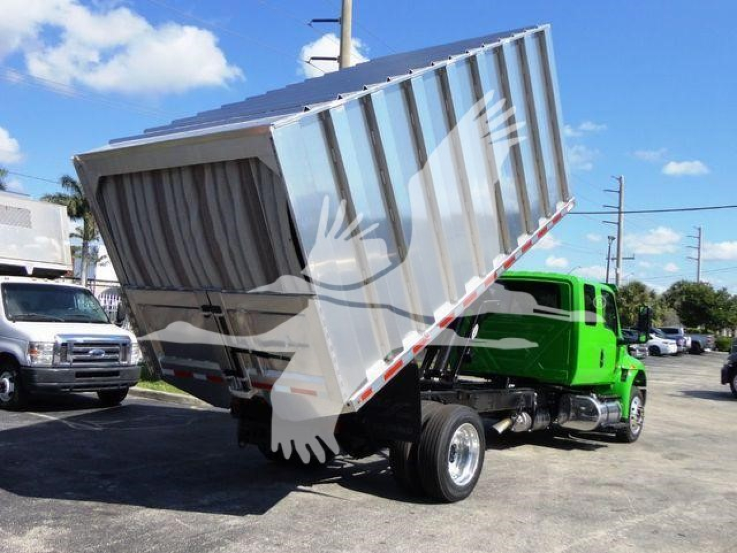 Truck chassis with raised dump bed on an International chipped truck showing grey dump body and green cab, rear wheels visible.