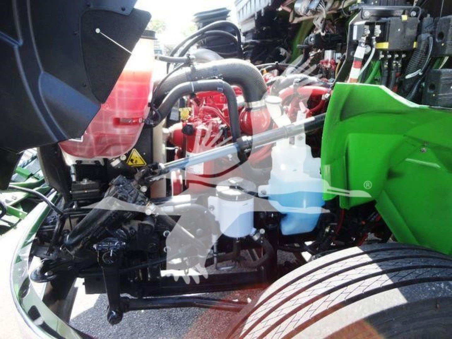 Truck engine bay showing coolant reservoirs and engine components in a green International MV chipper truck.