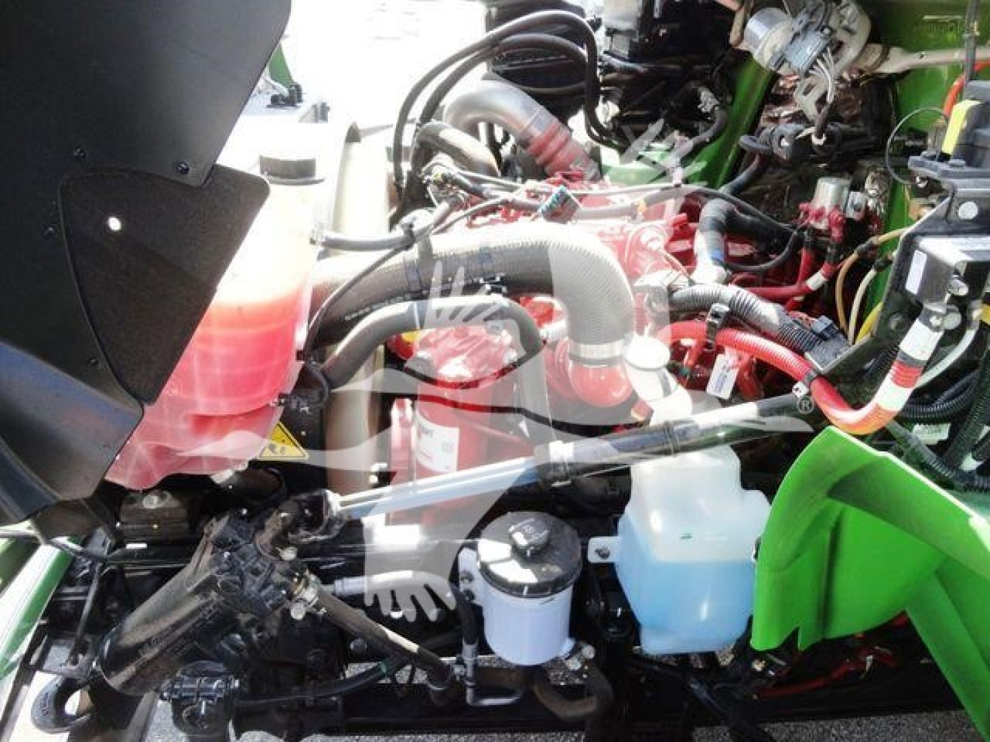 Engine bay of a 2023 International MV truck showing red engine, hoses, coolant reservoirs, and blue and white fluid containers.