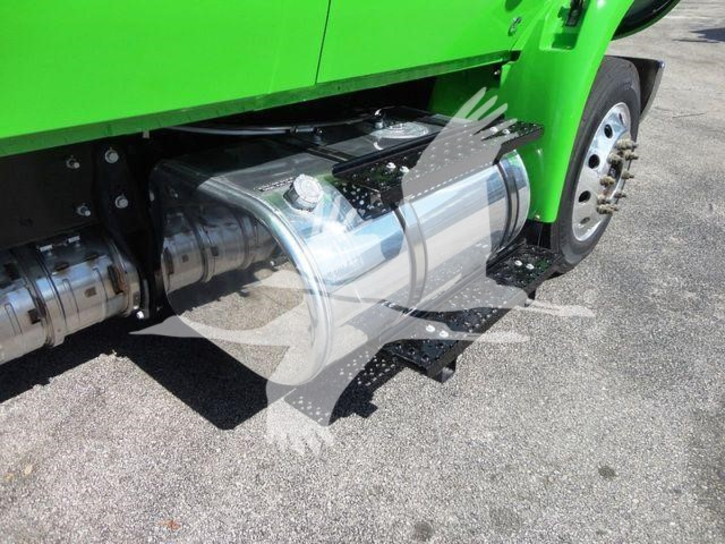 Truck side view showing fuel tank and underside components on a green cab, with wheel and step visible.
