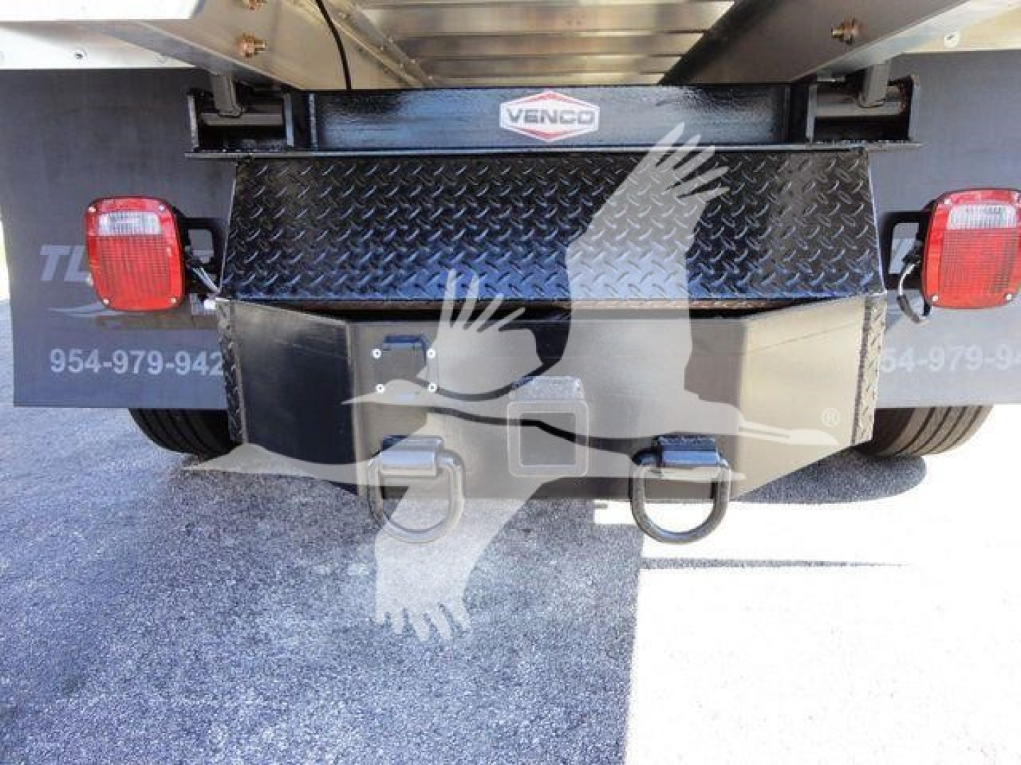 Rear of a heavy-duty truck showing a diamond-plate tailguard and two red taillights; Venco logo on the upper center; lower hitch and tool mounts visible.