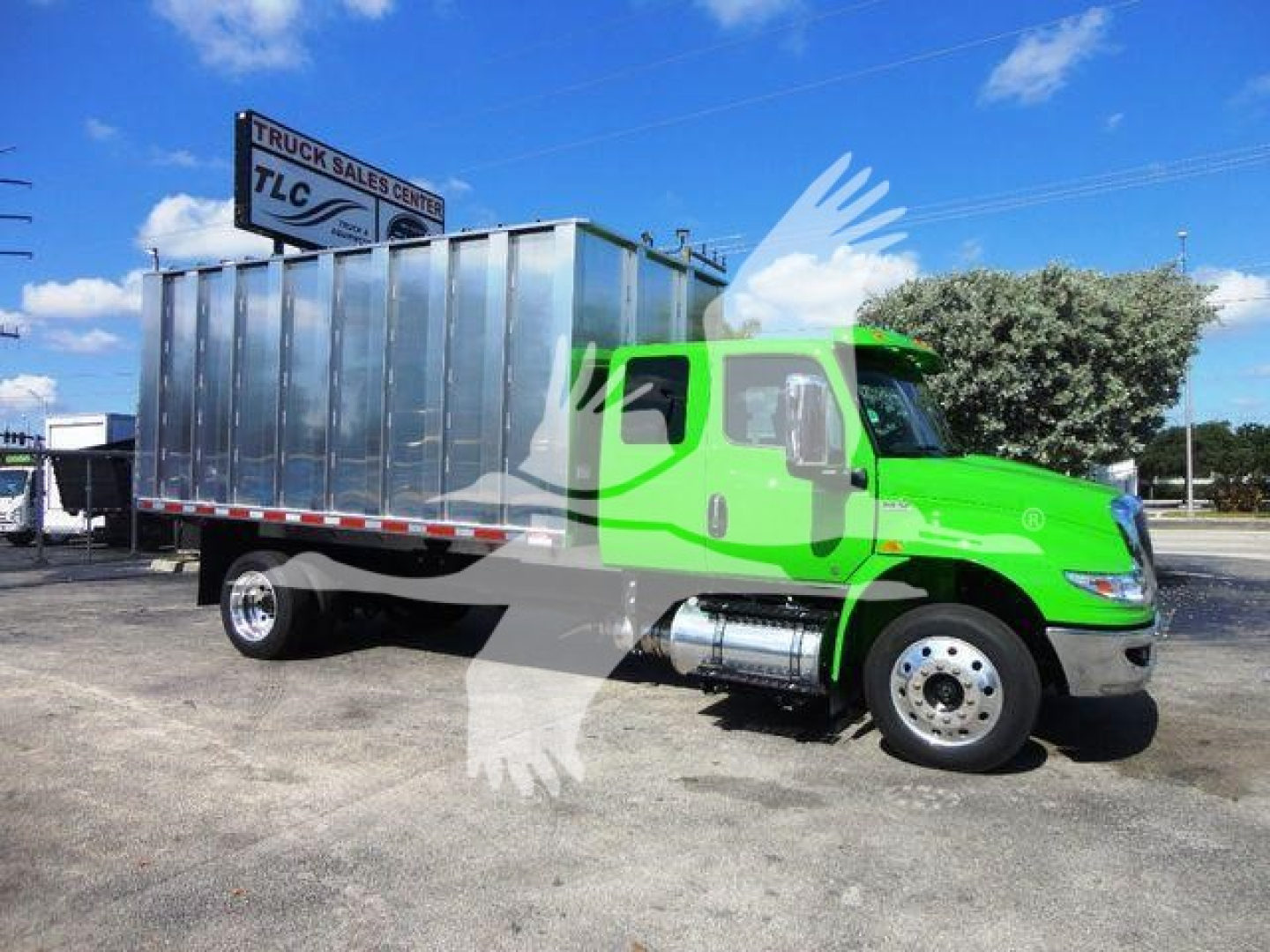 International MV truck with a bright green cab and a large silver cargo body, side view showing chrome fuel tanks and dual rear wheels.