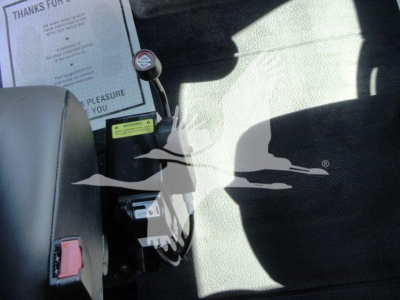Interior of a 2023 International MV chipper cab showing gear shift lever, control panels, and a document on the seat back with text.