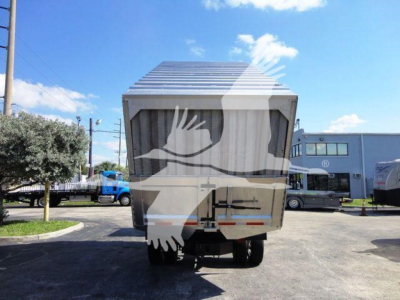 Rear view of a 2023 International MV truck dump body in a dealership lot showing tailgate and taillights.