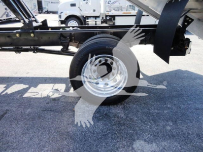 Truck chassis side view showing a wheel and part of the frame under carriage with hydraulic components and a trailer connection.