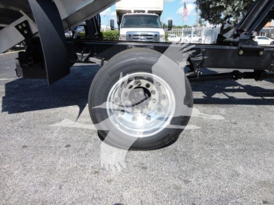 Wheel and undercarriage of a 2023 International MV chipper truck; steel wheel with hub, black chassis, and hydraulic components visible.