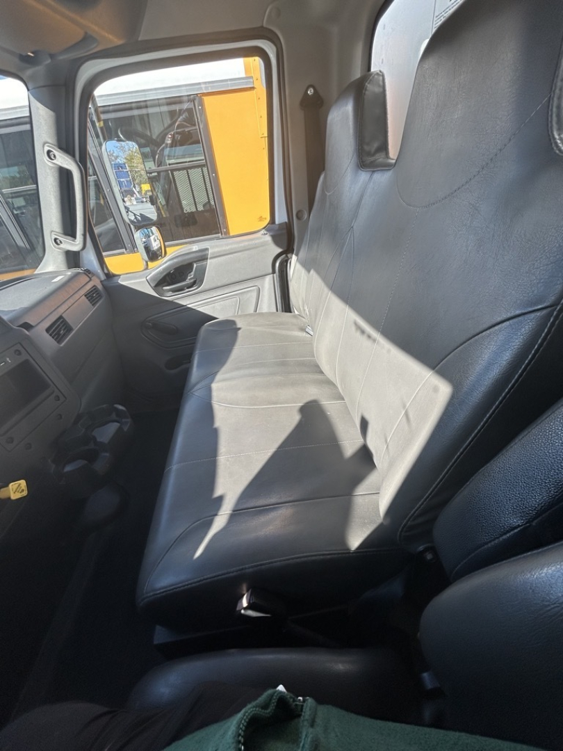 Cab interior of a 2020 International MV truck showing the driver and passenger seats with vinyl upholstery and dashboard visible.