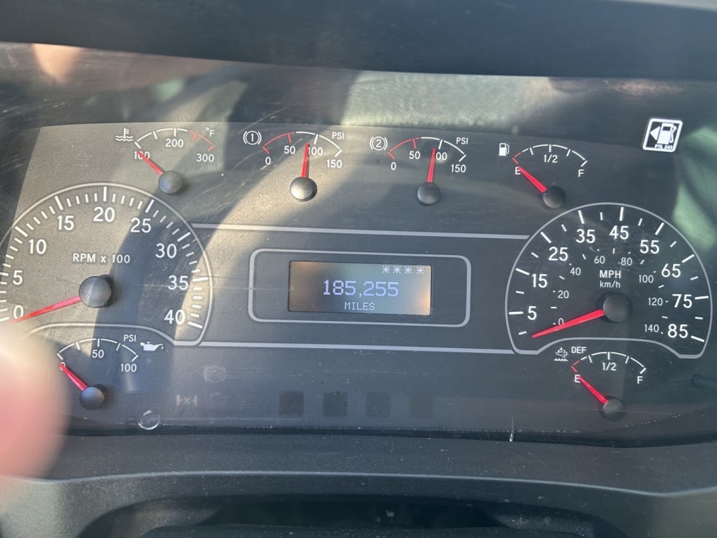 Truck instrument cluster showing speedometer, tachometer, and gauge needles; central odometer reads 185,255 miles; dashboard with multiple warning and indicator lights.