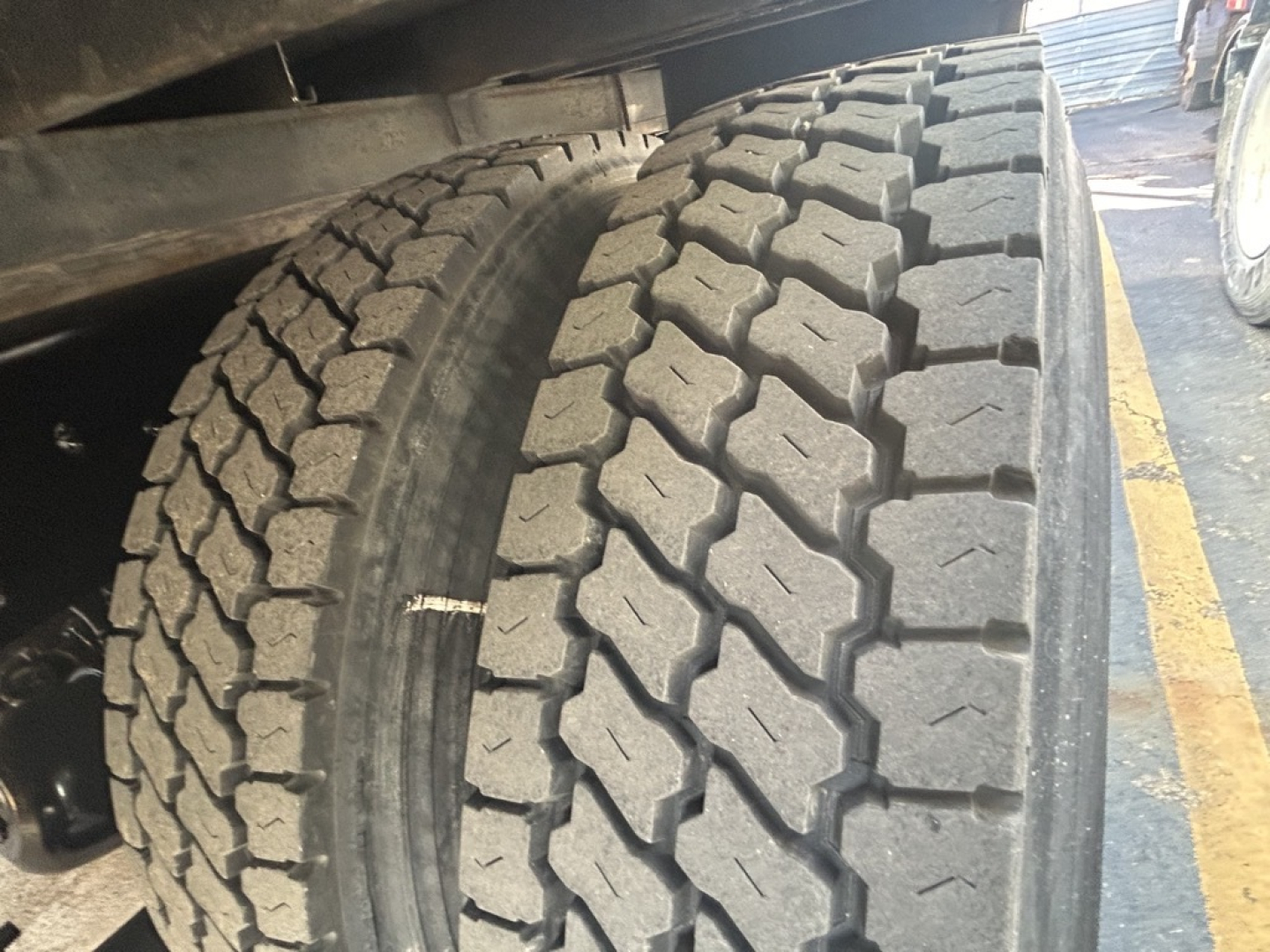 Truck tire close-up showing dual rear tires with deep tread pattern and sidewall details.