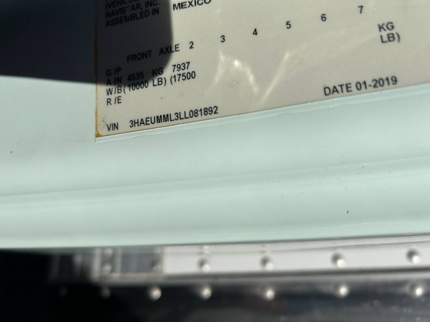 Truck VIN plate in the cab showing VIN 3HAEUMML3LL081892, date 01-2019, weight data, and labels on a white surface.