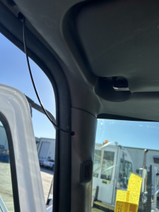 Cab interior A-pillar view of a 2020 International MV truck with sun visor and window; exterior lot with other trucks visible through the windshield.