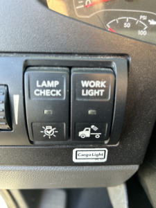 Truck dashboard switches: LAMP CHECK and WORK LIGHT buttons with icons, Cargo Light label below.