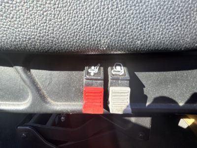 Seat air-release levers on dashboard with red and gray tabs, likely seat adjustment or lock controls.