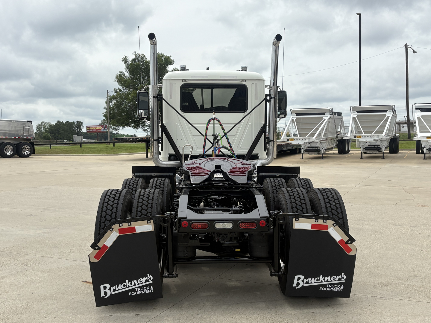 Truck rear view showing dual rear axles, fifth wheel, mud flaps with Bruckner's logo, and dual exhaust stacks.