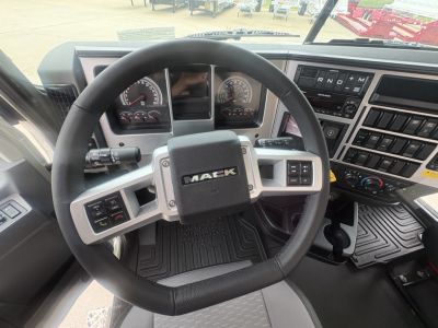 Mack PI64T truck interior showing steering wheel with Mack logo and instrument cluster, dashboard controls, and gear selector shifter.