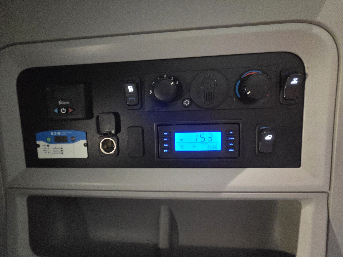 Dashboard panel of a Kenworth truck showing controls and a blue digital display.