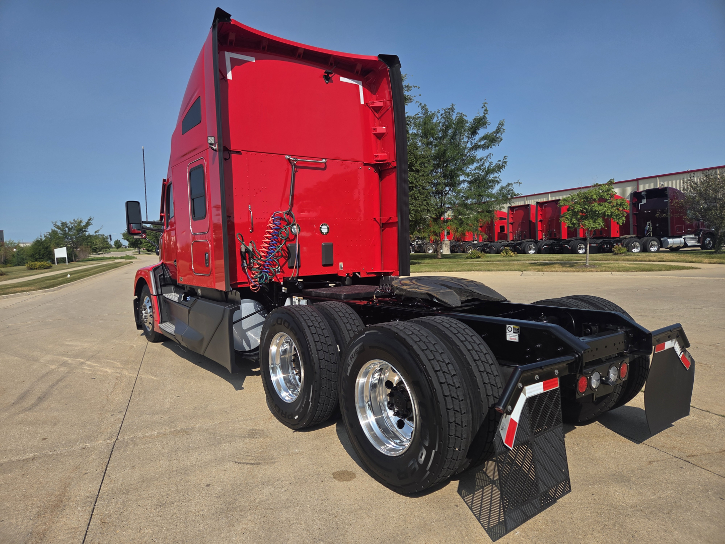Kenworth T680 tractor rear/side view showing red cab and dual rear axles with chrome wheels and plastic mudflaps.