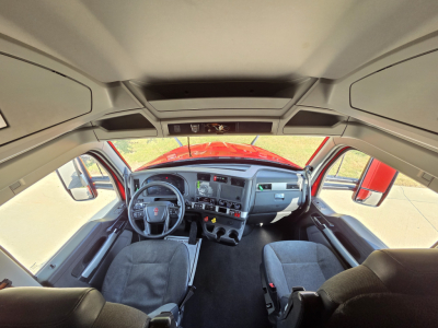 Kenworth T680 cab interior showing steering wheel, dashboard, and driver seat area.