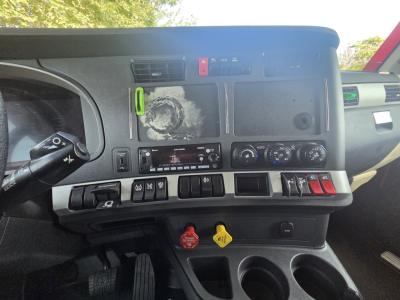 Kennworth T680 dash area showing control panel and dashboard switches with labels and gauge cluster; visible text includes various dials, warning icons, and a small radio display.