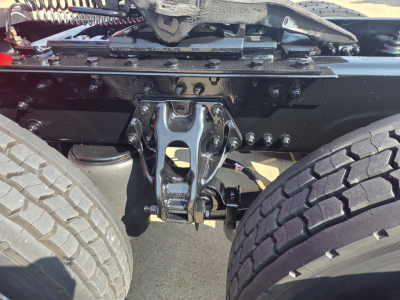 KENWORTH T680 rear view showing fifth wheel hitch and dual rear tires; visible components include a polished trailer air and mechanical linkage with bolts and brackets.