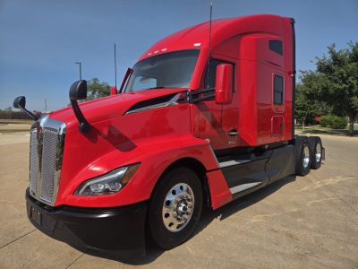 Kenworth T680 sleeper tractor in red, front three-quarter view showing cab, chrome grille, mirrors and wheel rims.