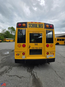 School bus rear view with yellow body, 'SCHOOL BUS' sign, emergency exit panel, and contact number on the back; 2014 Chevrolet Express G4500 mini school bus.