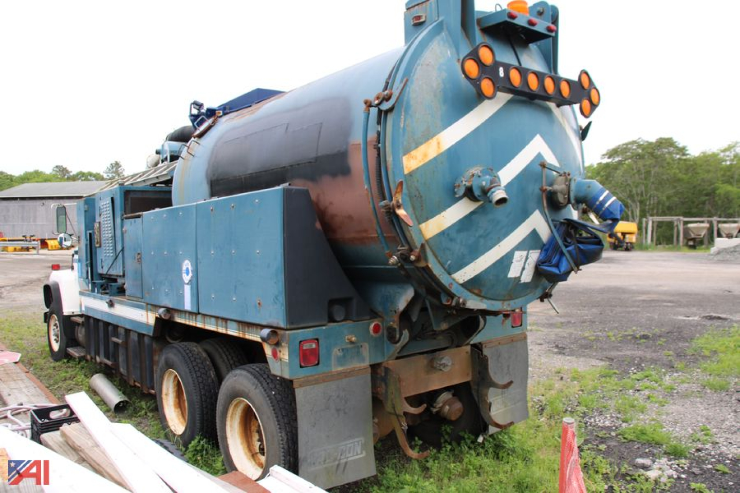 Vacuum truck rear and side view showing large cylindrical tank, rear blue hatch, and warning chevrons on the back of a 1996 Ford LNT8000 vac truck.