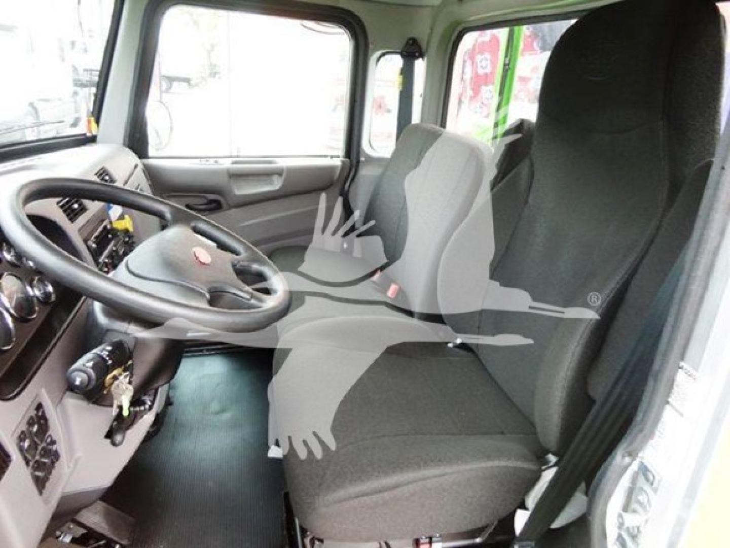 Truck cab interior showing steering wheel, dashboard, and two front seats.