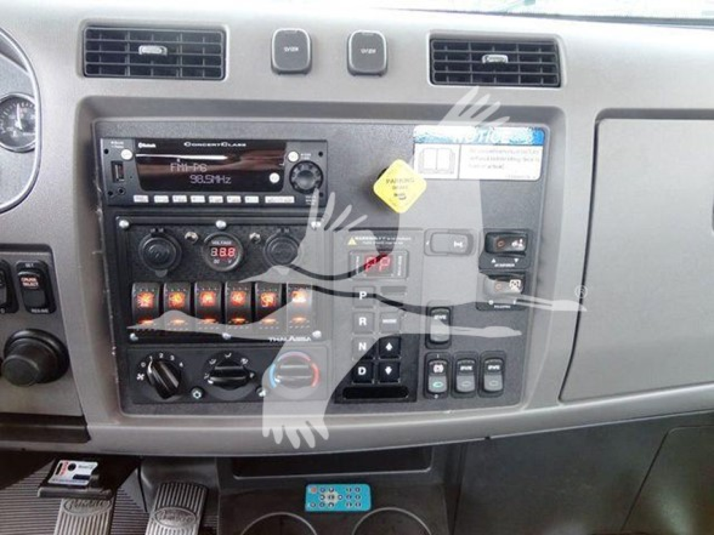 Peterbilt 337 dash cluster and center console with radio, climate controls, and gear selector, view of instrument panel from driver's seat.