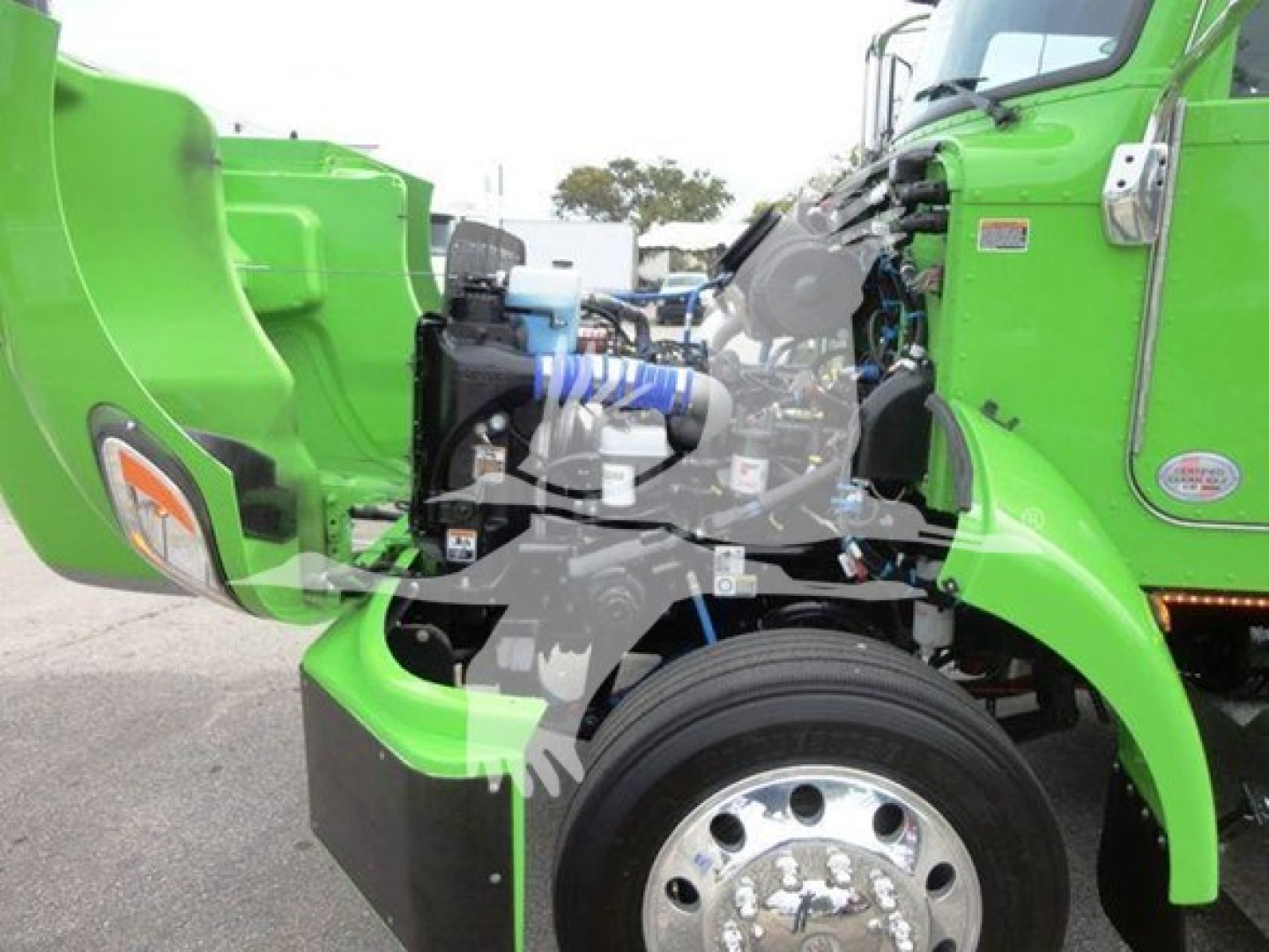 Peterbilt 337 truck engine bay view showing bright green body, exposed components, and front wheel with chrome hub, various hoses and blue clamps.