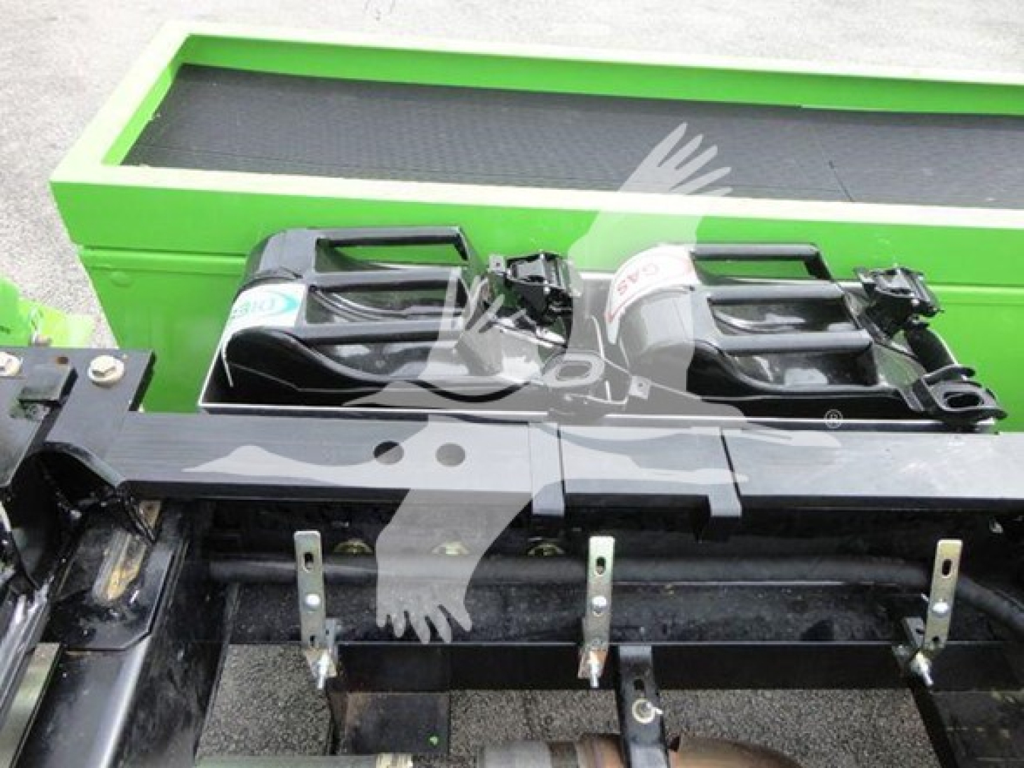 Peterbilt 337 rollback truck front display showing twin batteries and metal mounts, with a bright green equipment trailer in the background.