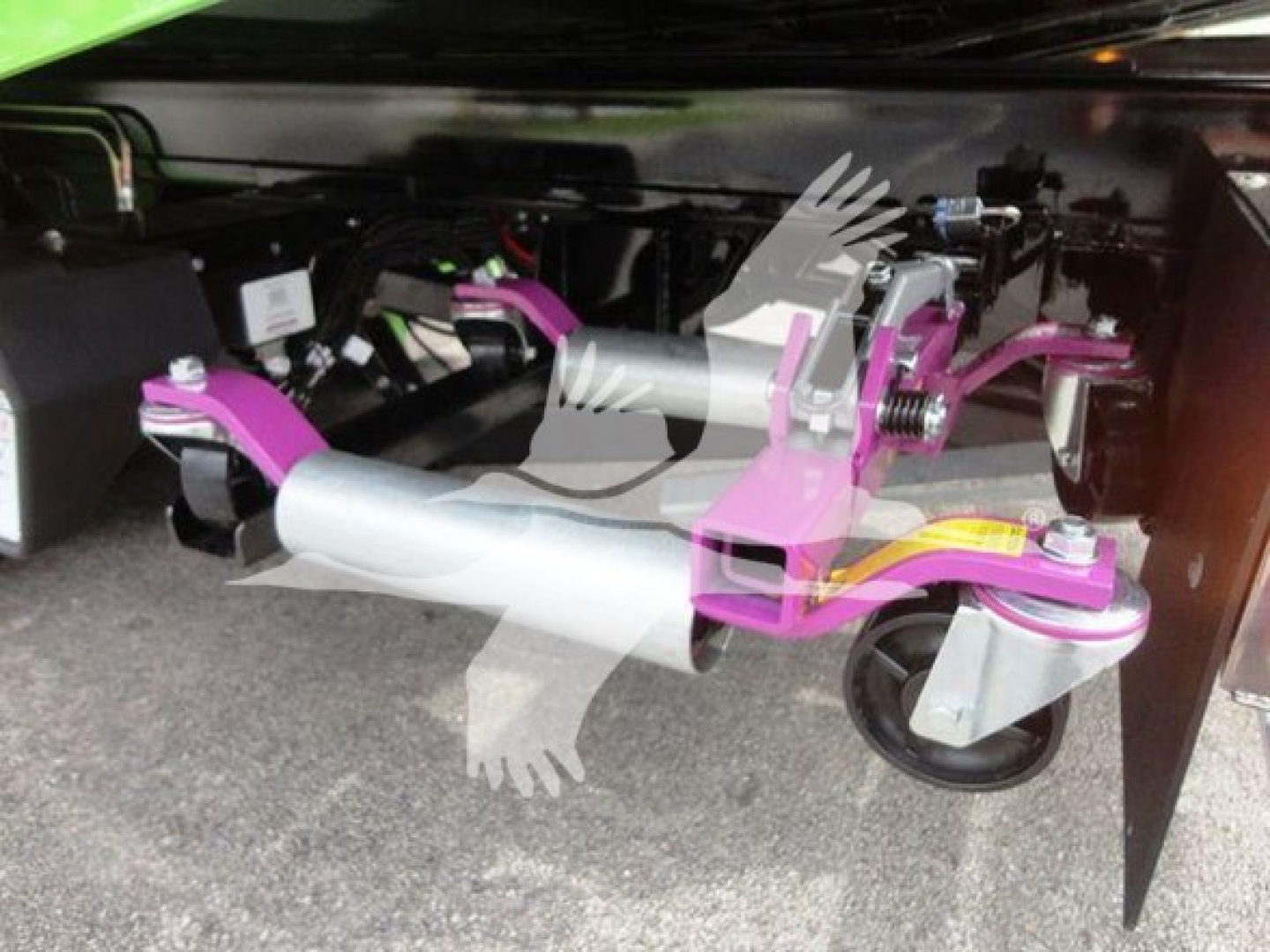 Truct rollback mechanism under a 2022 Peterbilt 337 showing pink/gray tripod stabilizer legs and wheel, side view of equipment-mounted support.