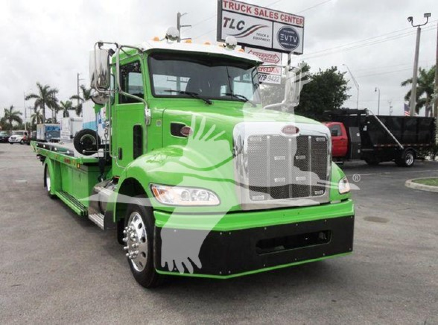 Peterbilt 337 rollback truck in bright green with white grille and graphics, front view, dealership lot.