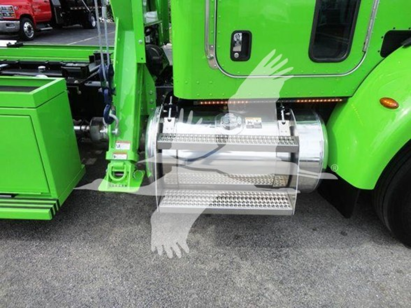 Green Peterbilt truck with a chrome cylindrical fuel or exhaust component under the cabin and metal steps; visible text on component.
