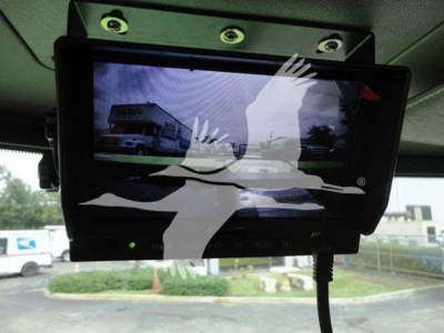 Truck monitor/display mounted in Peterbilt 337 cab showing a reflection of a rollback truck in the screen.